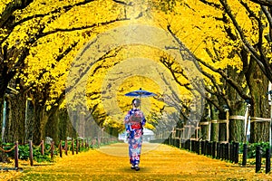 Beautiful girl wearing japanese traditional kimono at row of yellow ginkgo tree in autumn. Autumn park in Tokyo, Japan.