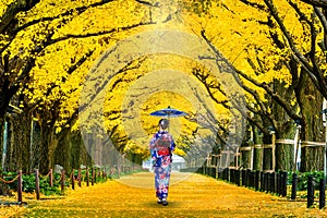 Beautiful girl wearing japanese traditional kimono at row of yellow ginkgo tree in autumn. Autumn park in Tokyo, Japan. photo