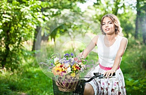 Beautiful girl wearing a nice white dress having fun in park with bicycle. Healthy outdoor lifestyle concept. Vintage scenery