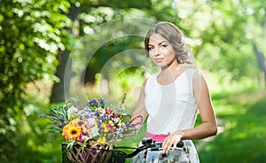 Beautiful girl wearing a nice white dress having fun in park with bicycle. Healthy outdoor lifestyle concept. Vintage scenery