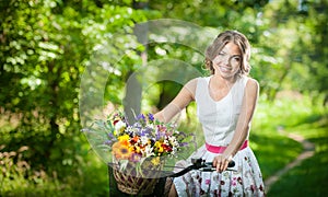 Beautiful girl wearing a nice white dress having fun in park with bicycle. Healthy outdoor lifestyle concept. Vintage scenery