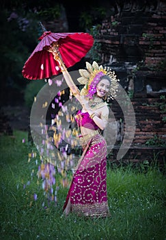 Beautiful girl wearing Thai dress and umbrella flower flow background old temple local country thailand