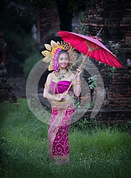 Beautiful girl wearing Thai dress and umbrella flower flow background old temple local country thailand