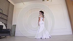 A beautiful girl in a wedding dress poses, coquettishly looks over her shoulder.