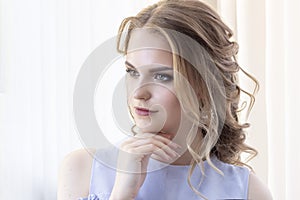 Beautiful girl with a wedding hairstyle looks at herself in the mirror, portrait of a young girl. beautiful make-up.