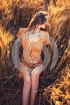 Beautiful girl in a wheat field. Natural sunlight during sunset