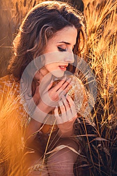 Beautiful girl in a wheat field. Natural sunlight during sunset