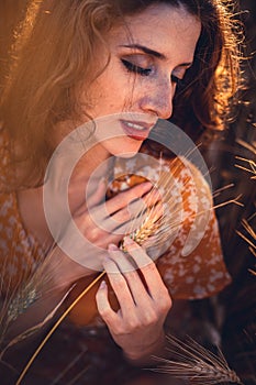 Beautiful girl in a wheat field. Natural sunlight during sunset