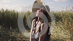 Beautiful girl in wheaten field posing smiling at camera. Portrait of a young attractive woman at sunset