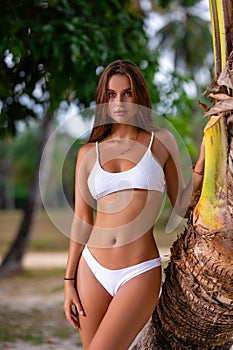 Beautiful girl in white bikini posing at the tropical beach