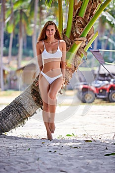 Beautiful girl in white bikini posing at the tropical beach