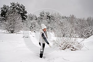 Beautiful girl in white clothes in the winter forest. Active recreation during the winter