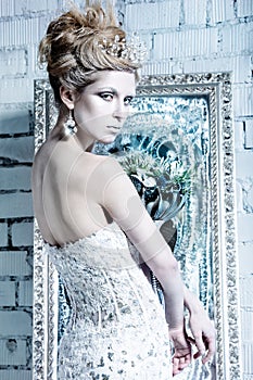 Beautiful girl in white dress in the image of the Snow Queen with a crown on her head.