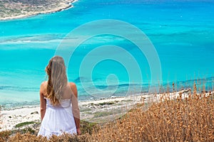 The beautiful girl in the white dress looks spellbound at the spectacular turquoise sea lagoon photo