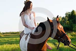 Beautiful girl in white dress sitting on horse