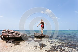 Beautiful Girl White Hair and red swimmingsuit staying on rock beach, relaxing and enjoy freedom.