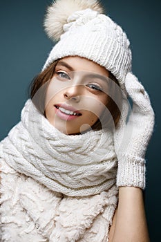 Beautiful girl in a white knitted hat with fur pompom. Model with gentle nude make-up. Cozy winter picture.