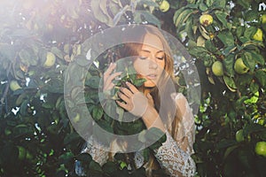 Beautiful girl in white lace dress in apple garden