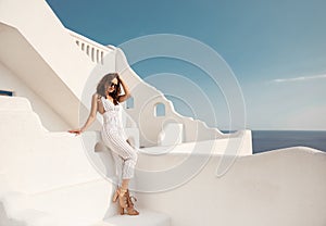 Beautiful girl in white outfit. Model on summer vacation enjoying time on Santorini island Greece. Brunette posing on white