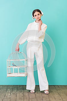 beautiful girl in white outfit with parrot in cage