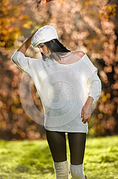 Beautiful girl in white posing in park in autumn day. Beautiful elegant woman with white cap in autumnal park