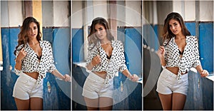 Beautiful girl with white shirt and white shorts posing in old hall with columns blue painted. Attractive long hair brunette