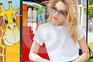 Beautiful girl in a white T-shirt and shorts in dzhisovyh amusement park in sunglasses , hair develops wind