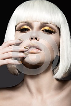 Beautiful girl in a white wig, with gold makeup and nails. Celebratory image. Beauty face.