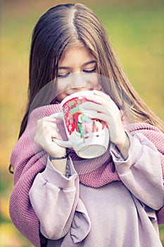 Beautiful girl with winter fluffy scarf holding a Christmas mug