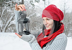 Beautiful girl in winter forest with lantern