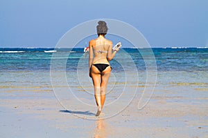 Beautiful girl wolking in the beach with a book