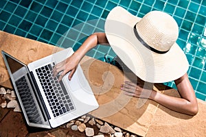 Beautiful girl woman in bikini relaxing pool and using laptop on edge while smiling