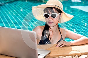 Beautiful girl woman in bikini relaxing pool and using laptop on