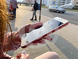 Beautiful girl woman sitting and holding a modern white mobile phone smartphone in her hand with fingers with a beautiful manicure