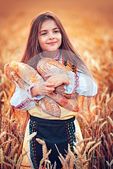 Beautiful girl woman in traditional Bulgarian folklore dress holding homemade bread in wheat field