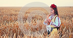 Beautiful girl woman in traditional Bulgarian folklore dress holding homemade bread in wheat field, agriculture and homegrown food