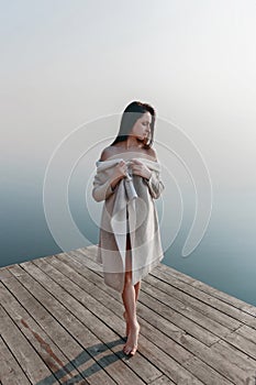 Beautiful girl on wooden pier near the water