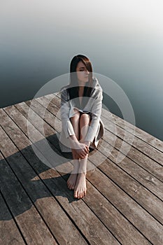 Beautiful girl on wooden pier near the water