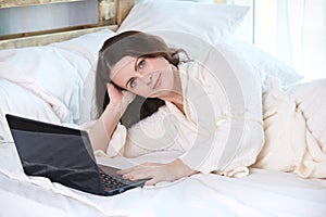 Beautiful girl. Work at home. Black notebook. White Bed