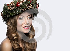 Beautiful girl with a wreath of Christmas tree branches and cones. New Year image. Beauty face.