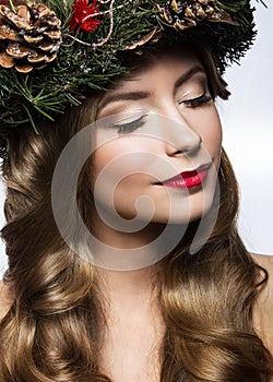 Beautiful girl with a wreath of Christmas tree branches and cones. New Year image. Beauty face.