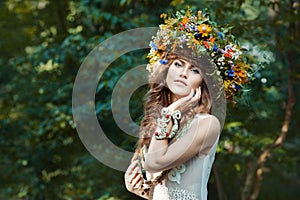 Beautiful girl with wreath on the head of field flowers.