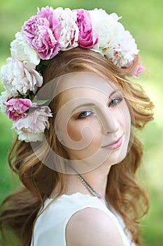 beautiful girl in a wreath of peonies