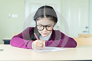 Beautiful girl writing on a blank paper in classroom