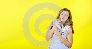Beautiful girl on a yellow background holds in her arms and hugs a little cute kitten