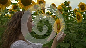 Beautiful girl and yellow flowers in summer. Caucasian woman walks in nature. Portrait of a young woman on a field among