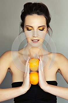 Beautiful girl with yellow makeu-up holding two oranges