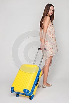 Beautiful girl with a yellow suitcase loves to travel