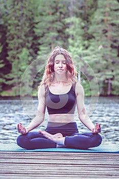 Beautiful girl in a yoga pose on the lake. Lotus position ,  Padmasana. The concept of appeasement,  healthy lifestyle