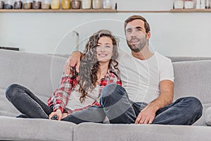 Beautiful girl and a young man sitting on the couch and watch TV. People relax on the couch.Young man in glasses and